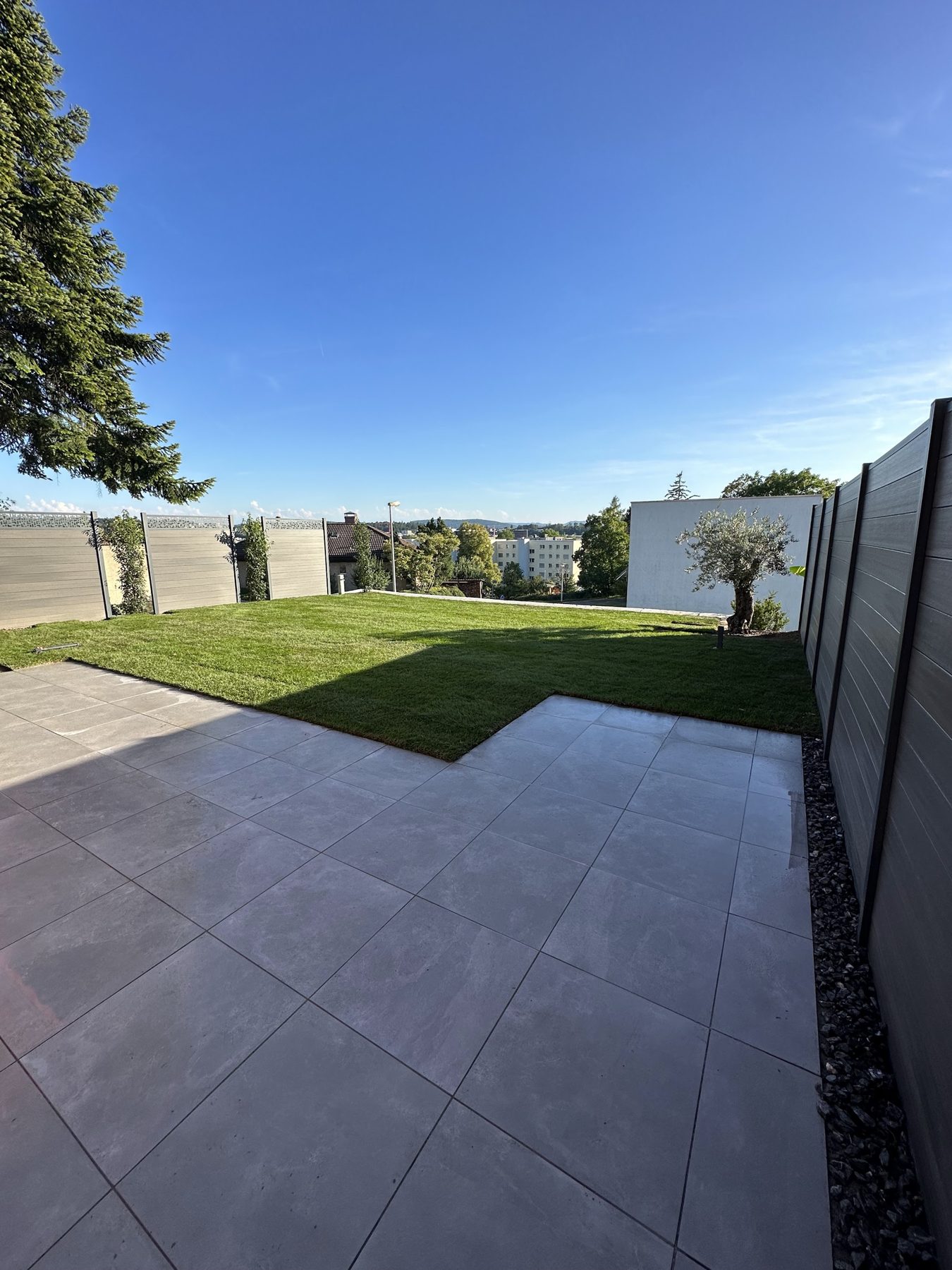Grossformatige Terrassenplatten neben einer Rasenfläche